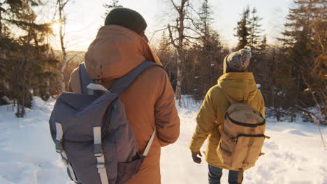 hikers in a snowy forest at sunset