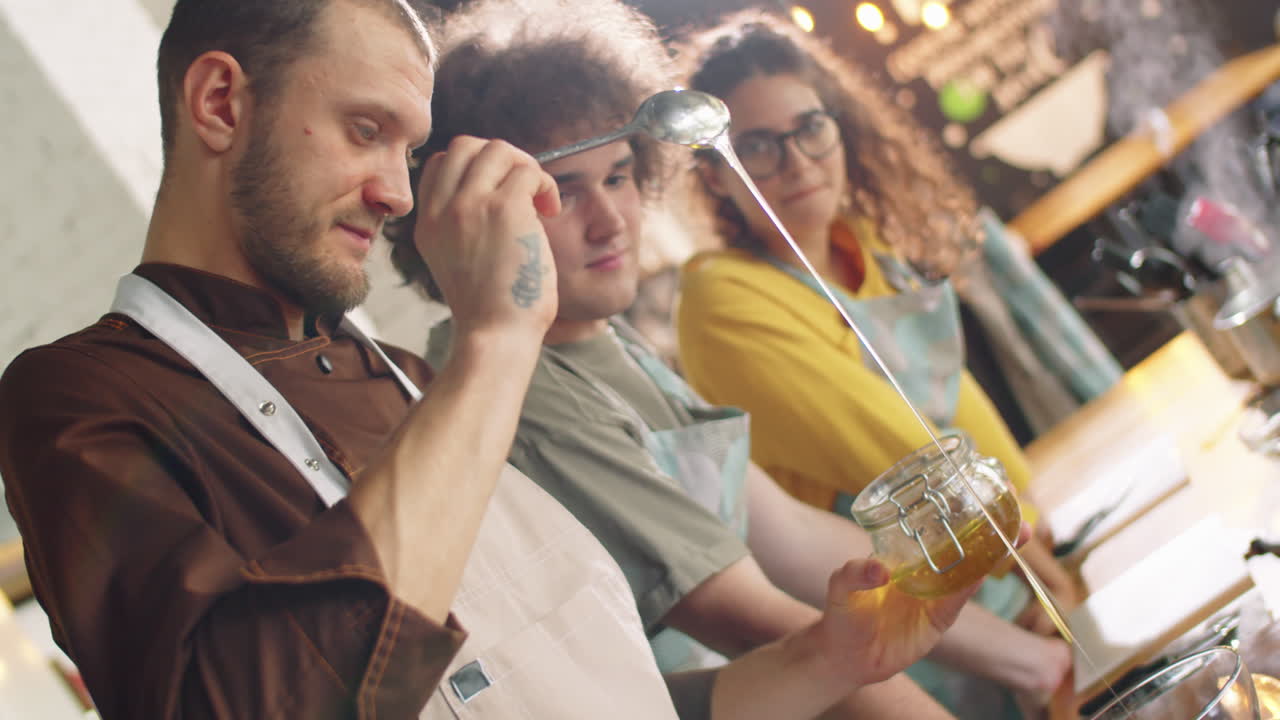 chef añadiendo miel al cuenco y hablando con los estudiantes en la clase de cocina