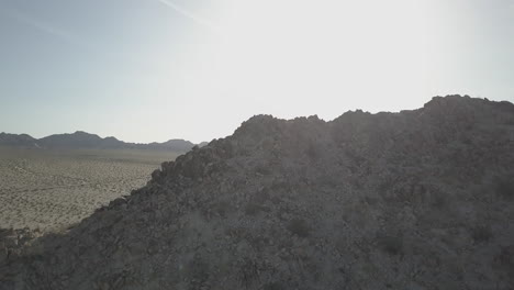 revealing drone shot coming from behind a mountain and looking over death valley usa america on a sunny day with sun flares log