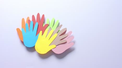 Close up of hands together made of colourful paper on white background with copy space