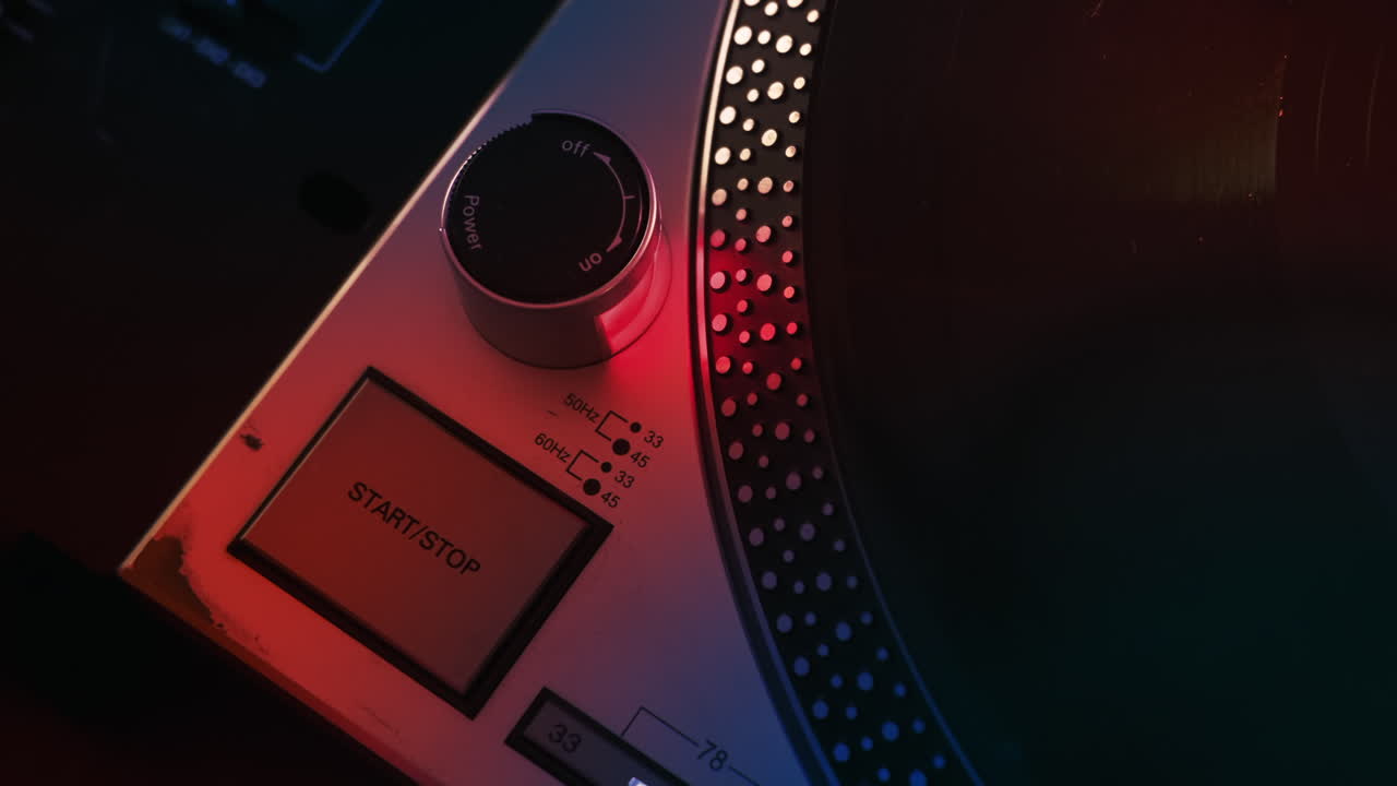 Man starting record player, pushing start button. Neon red illumination around