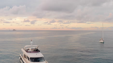 Drone-flies-between-moored-boats-in-the-middle-of-the-ocean,-unveiling-an-infinite-expanse-of-water-and-sky