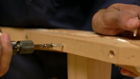 closeup shot of workers assembling wood furniture with screws, woodworking manufacturing industry