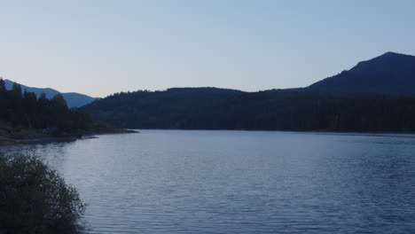 4k timelapse of sunrise , mountain landscape, lake , green mountains rises above calm expanse of water