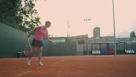 slow-motion-side-view-of-a-young-athlete-trains-the-serve-of-the-tennis-ball.-A-teenage-athlete-is-playing-tennis-on-a-court.-An-active-girl-is-powerfully-hitting-a-ball-during-sport-practicing