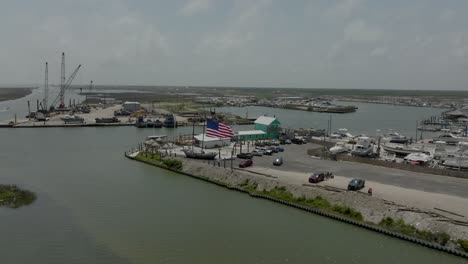Aerial-view-of-a-waterfront-restaurant-with-a-big-American-flag-in-4K