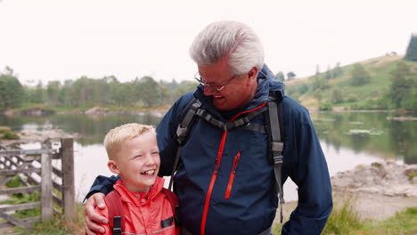 grandfather and grandson laughing, standing at the shore of a lake, close up, lake district, uk
