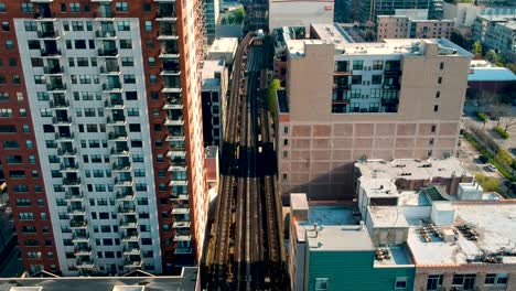 eine luftaufnahme der chicagoer „l“-linie zusammen mit wohn- und geschäftsgebäuden