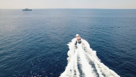 Speedboat-sailing-through-blue-sea,-aerial-tracking-view