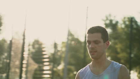 a concentrated basketball player trying to spin ball on his finger in an outdoor basketball court at sunset