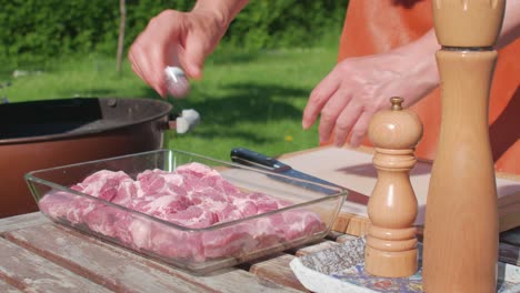 male hands spice up pork butt chops with salt and ground black pepper from pepper mill