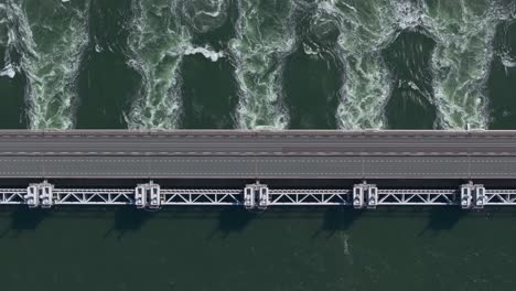 Top-down-of-water-flowing-through-the-opened-sluices-of-the-Eastern-Scheldt-storm-surge-barrier-in-Zeeland,-aerial