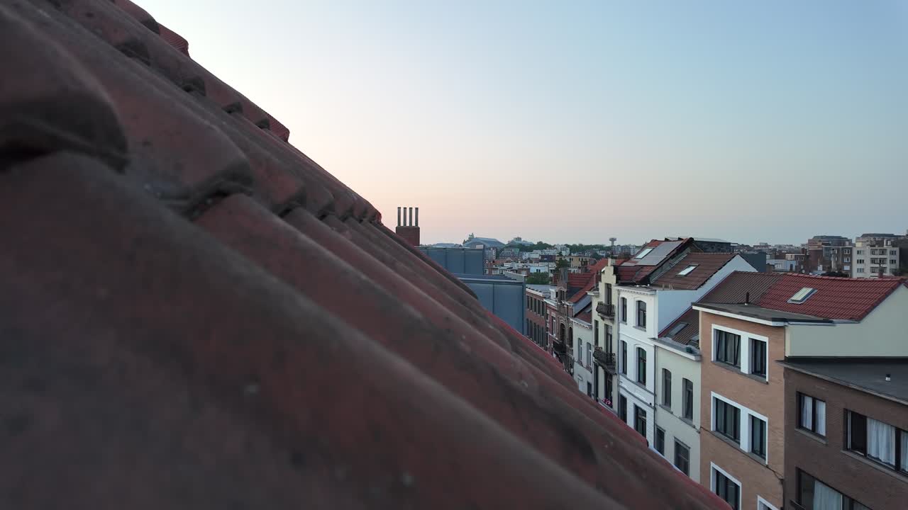 Camera moves forward over Brussels rooftops at sunset