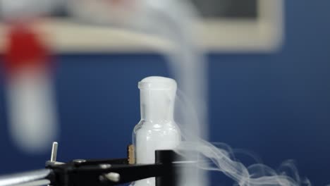 en un metódico primer plano a cámara lenta, un tubo de ensayo revela una reacción química distinta, a medida que los vapores blancos ascienden, personificando la precisión y la complejidad de la investigación de laboratorio