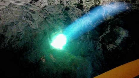 kayakista observando un haz de luz que ilumina algunas rocas en el agua dentro de una cueva marina, isla de vis, mar adriático, croacia