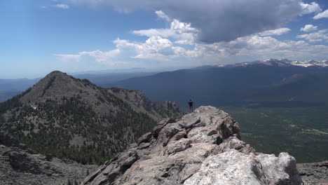 Lonely-Man-Walking-on-Rocky-Mountain-Summit-With-Amazing-View-of-Landscape-on-Sunny-Summer-Day