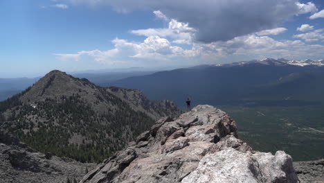 lonely man walking on rocky mountain summit with amazing view of landscape on sunny summer day