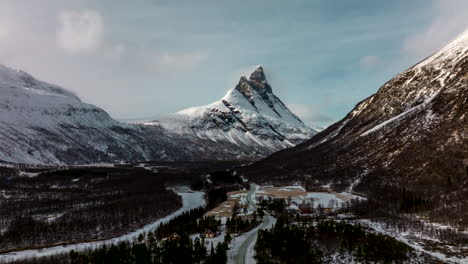 Backwards-drone-hyperlapse-in-snowy-landscape,-view-of-Otertinden-peaks