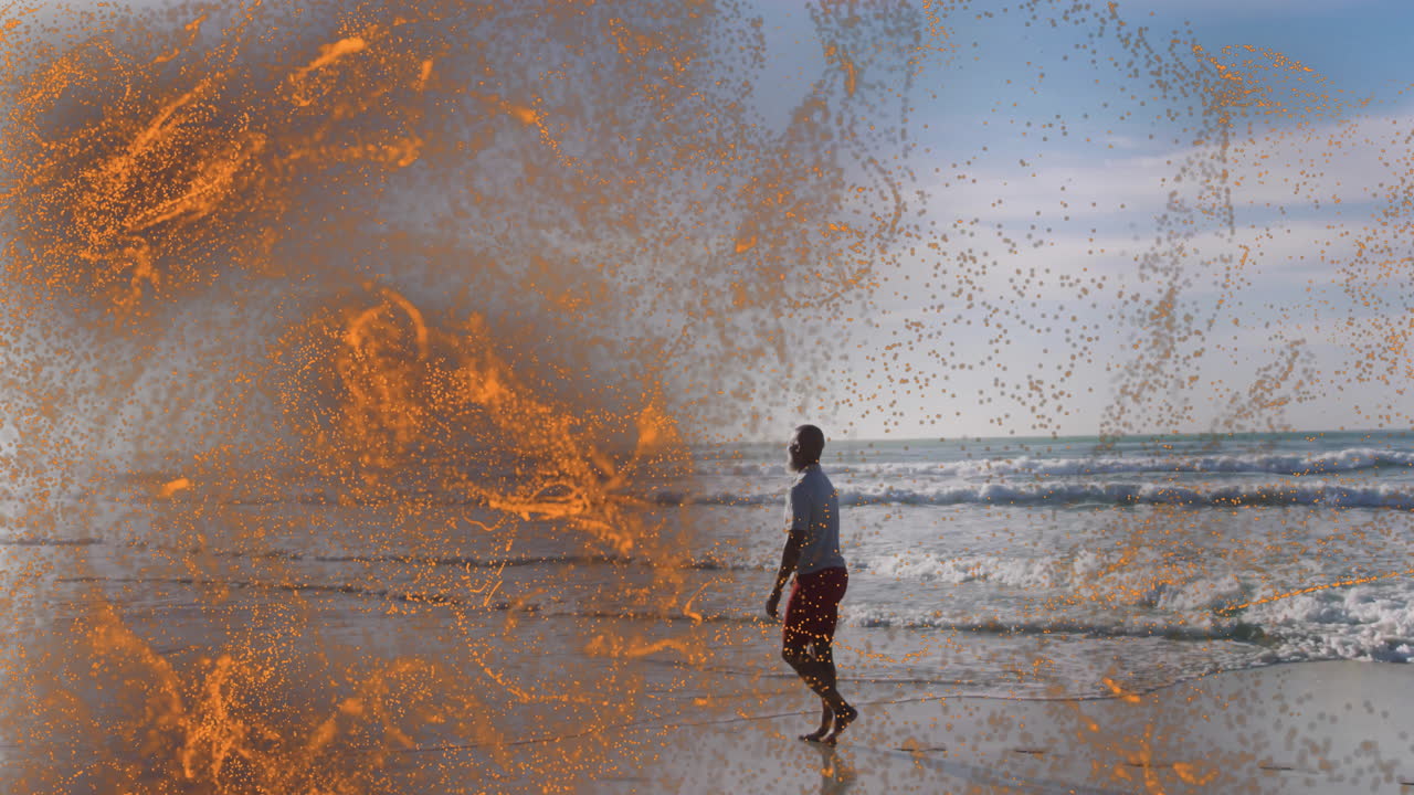 Ein Mann geht am Strand, umgeben von einer dynamischen orangefarbenen Partikelanimation.
