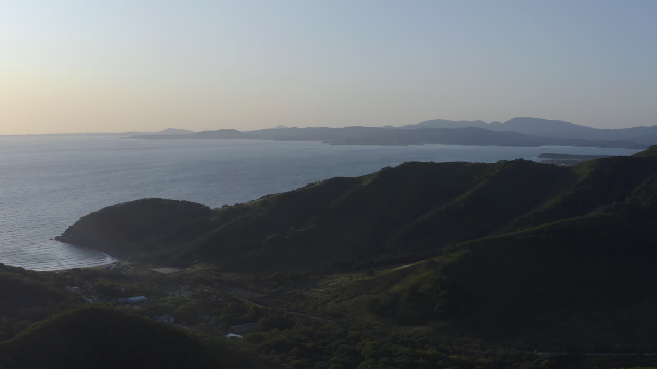 Vista di una baia circondata da montagne e colline verdi al tramonto, Russia, Estremo Oriente.