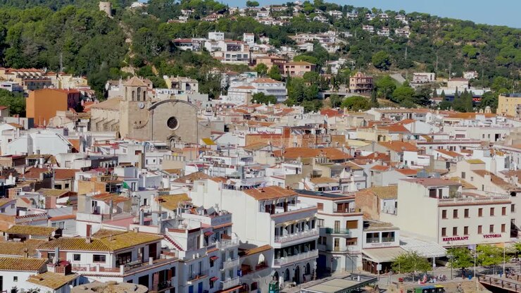 Baia di Tossa de Mar vista dal castello alla spiaggia con sabbia grossolana e acqua di mare blu turchese, antico borgo medievale di pescatori fortificato sul Mar Mediterraneo