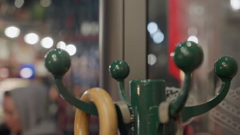 close-up of an umbrella handle on a rack with blurred lights and people in the background, with reflection of light on the side glass