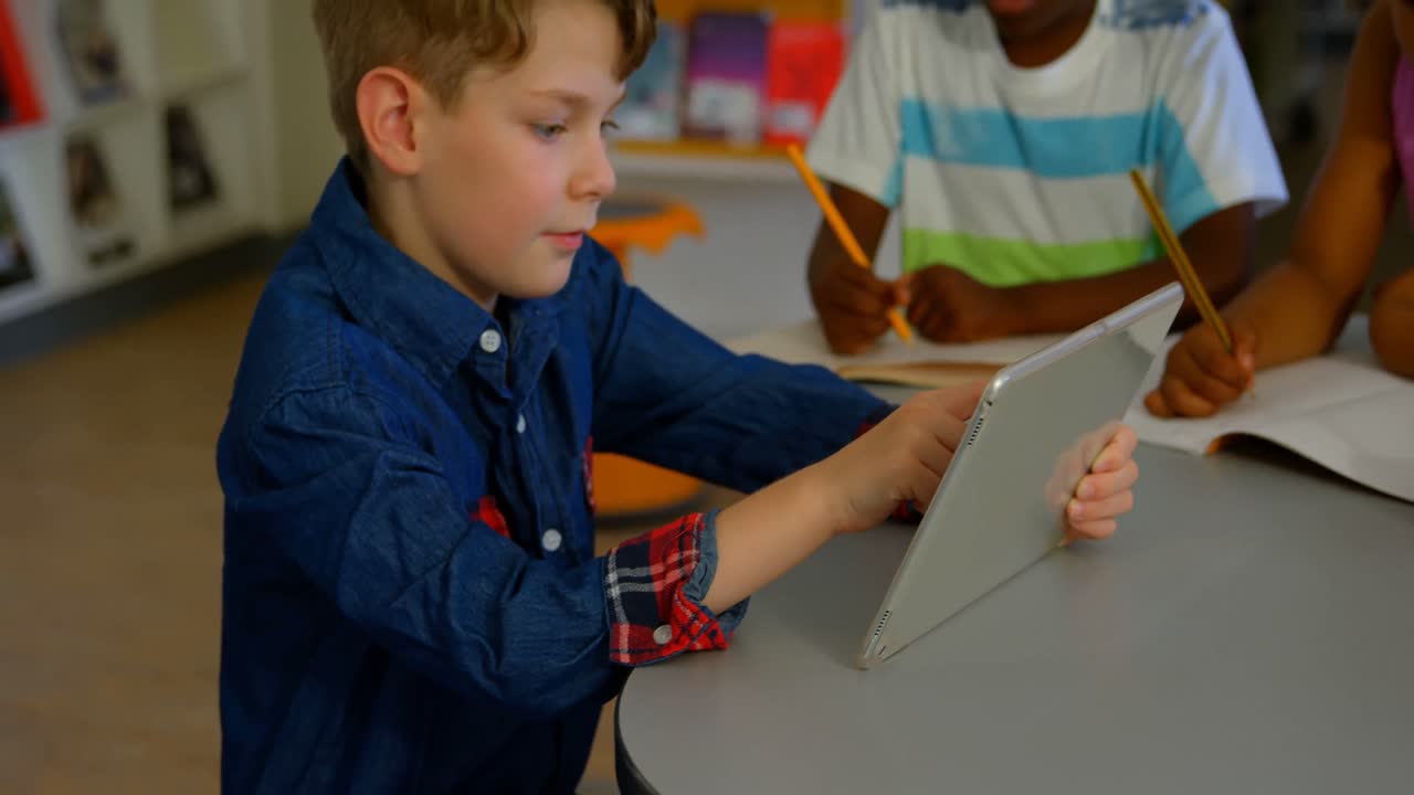белый школьник, использующий цифровой планшет в школьной библиотеке 4k