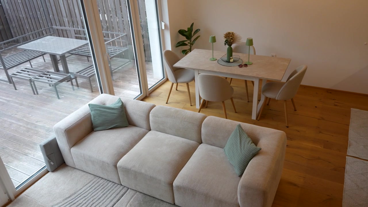 Modern vacation rental interior with cozy living room, sofa, dining table, minimalist decor, large windows and outdoor patio, hospitality and property.