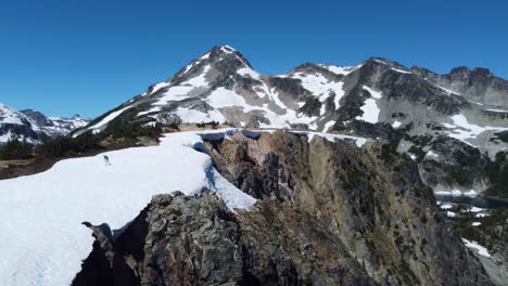 Drone-Aéreo-Hombre-Caminando-En-La-Nieve-En-La-Cima-De-La-Montaña-En-Las-Cordilleras-Del-Pacífico-En-Columbia-Británica-Canadá-4k