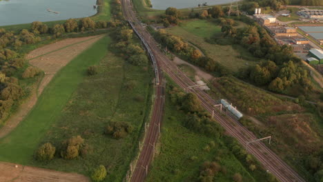 Pan-up-aerial-shot-of-a-train-heading-over-the-Walthamstow-wetlands-towards-Tottenham-hale-London