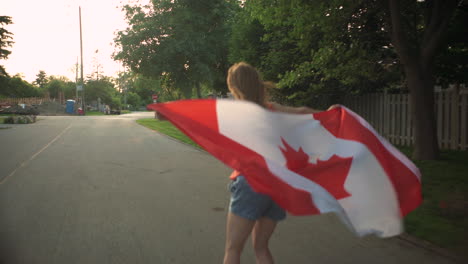 girl rides a longboard while waving the canadian flag proudly behind her