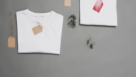 video of flat lay of white t shirts with tags and copy space on grey background