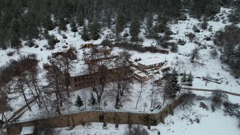 Old-church-surrounded-by-forest-trees-and-mountain-covered-in-snow,-St