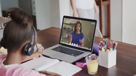una estudiante diversa teniendo clase en una llamada de video portátil con una maestra en cámara lenta