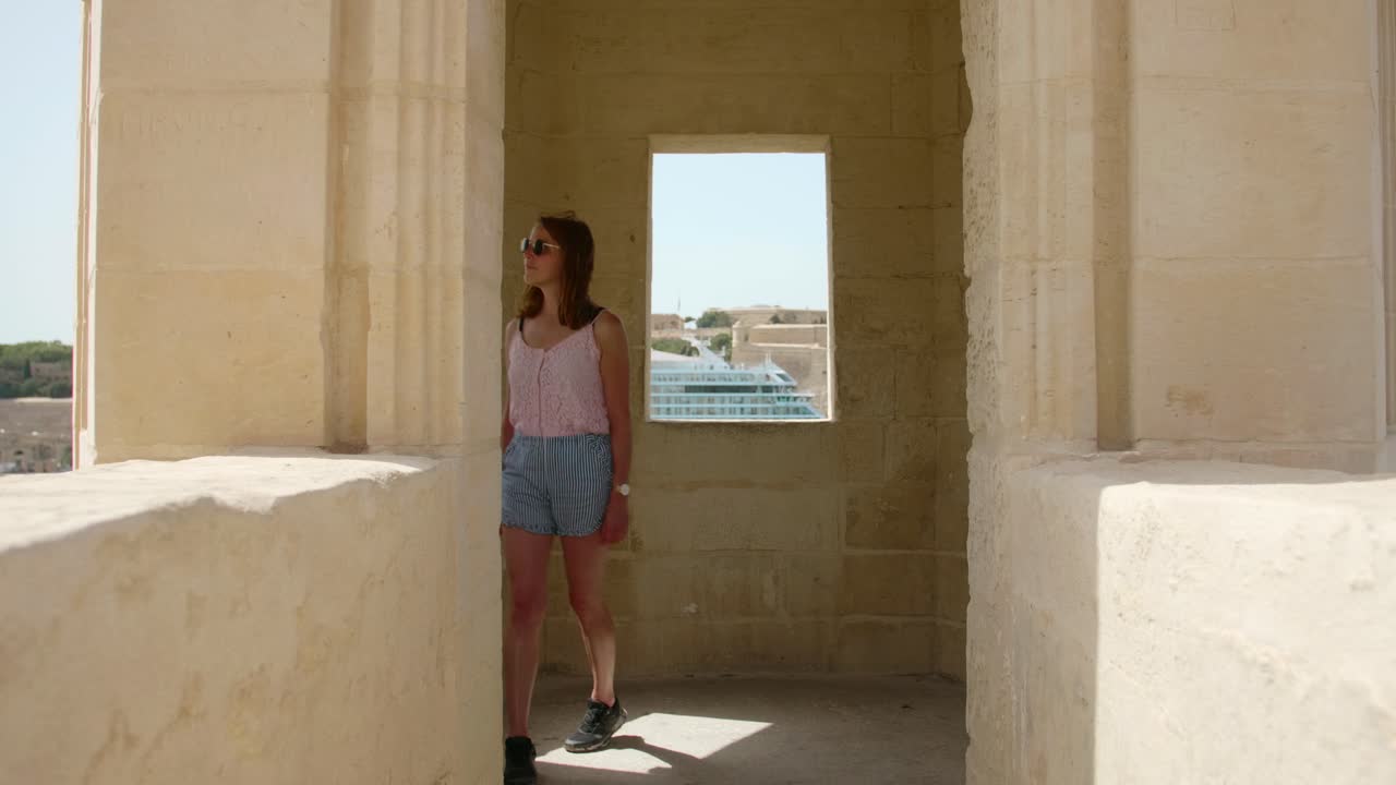 Young tourist woman visiting an old guard tower near the Gardjola Gardens in the city of Senglea (Isla), Island of Malta.