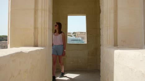 young tourist woman visiting an old guard tower near the gardjola gardens in the city of senglea (isla), island of malta.