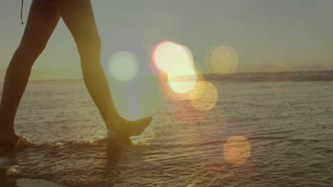 animation of light spots over caucasian woman walking on beach