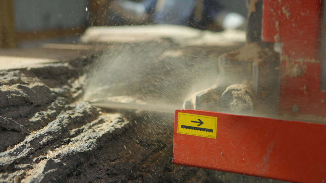 제재소에서 큰 톱날이 나무 줄기를 슬로우 모션으로 잘라냅니다.