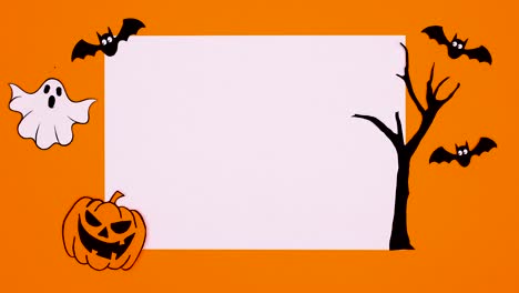 writing happy halloween text on white paper with creepy halloween decorations around. stop motion