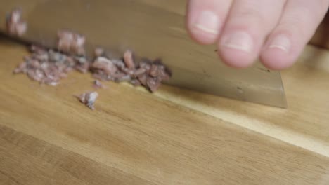 shot of chopping anchovies with a knife on a cutting board