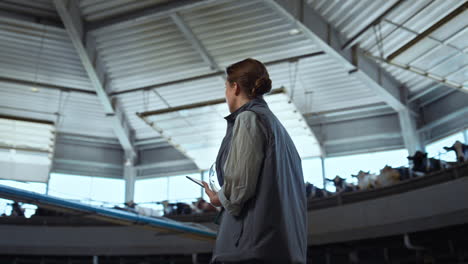 Manager-inspecting-milking-parlour-alone.-Focused-worker-holding-pad-computer.