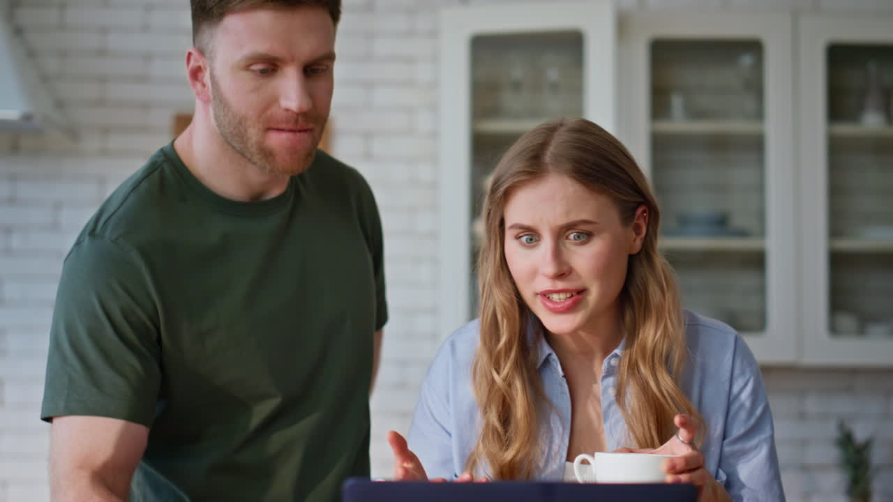 Smiling spouses looking computer in kitchen enjoying morning together closeup