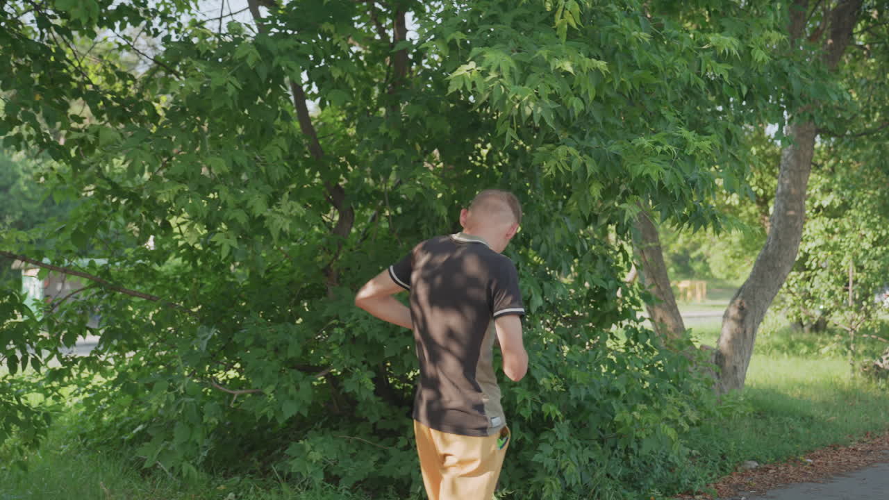 Man Searches Outdoors, Person Diligently Searching Inside Bag Amidst Lush Bushes During Summer, Man Appears Focused As He Rummages Through His Satchel Amidst Dense Foliage On Warm Summer Day