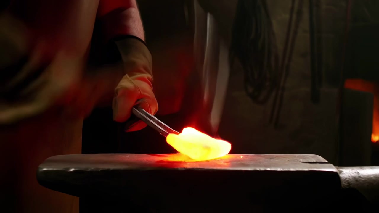 A blacksmith works beside bright flames, striking a heated metal piece on an anvil inside a dark workshop with smoke, warm orange light, and a focused