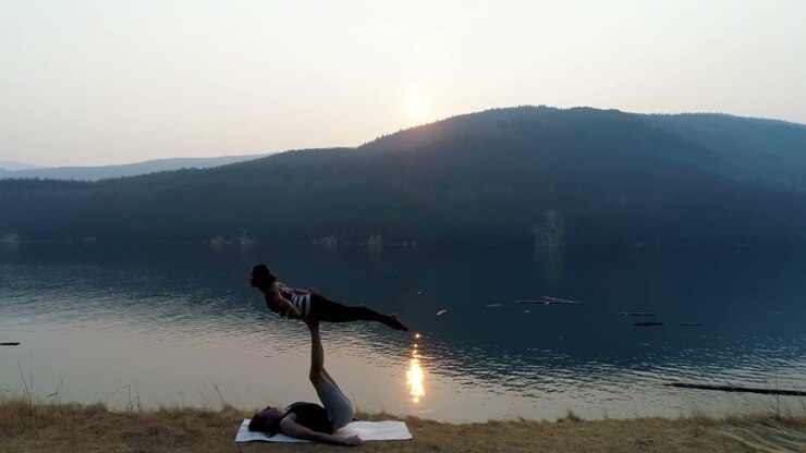 Donne che praticano acroyoga in riva al lago 4k
