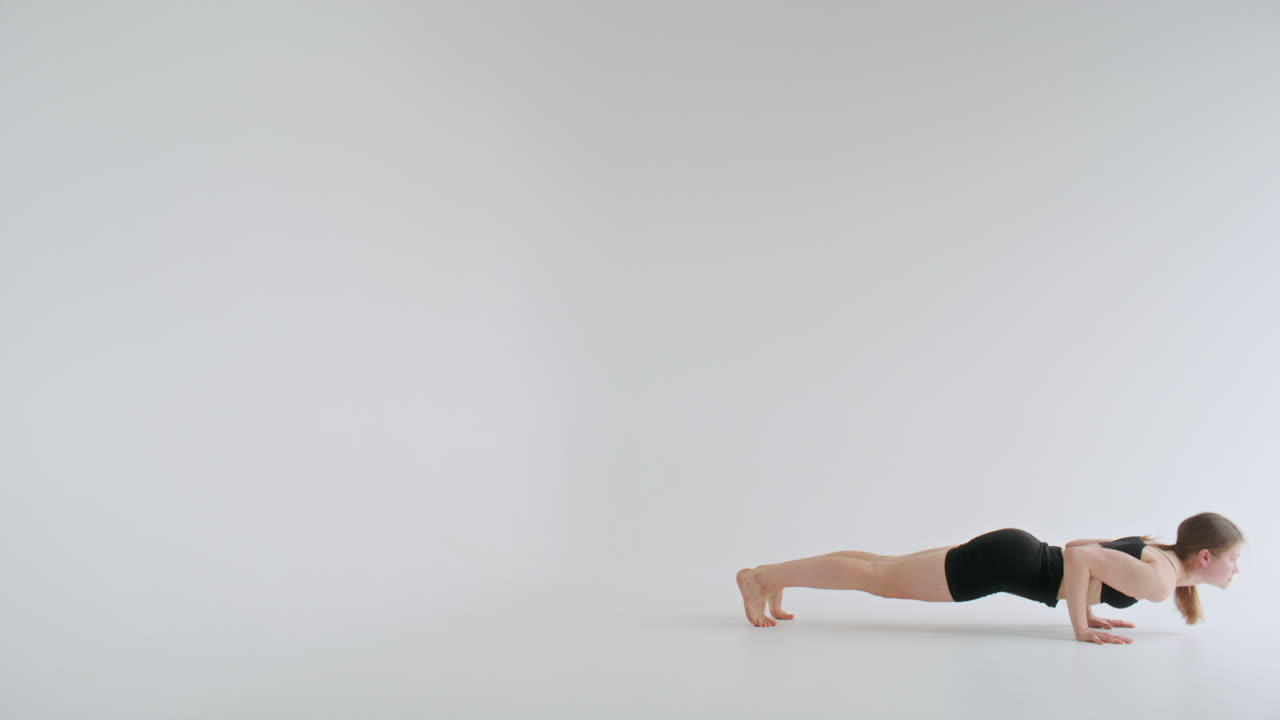 Giovane donna che pratica Vinyasa Flow Yoga in uno studio minimalista