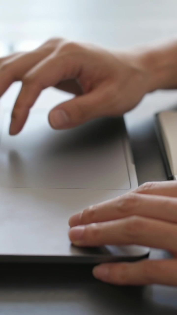 Video verticale: Avambracci maschili che sollevano un laptop sulla scrivania, raggiungono il telefono e si preparano a digitare.