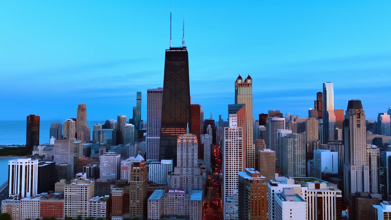Diverse altezze degli edifici nel centro di Chicago, Illinois, Stati Uniti. Un lungo viale è pieno di auto con i fari accesi. Metropoli al tramonto vista dall'alto.