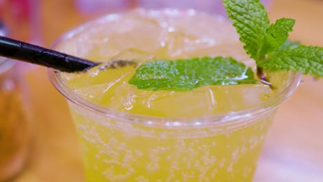 close up view of a mixed alcoholic beverage with a mint coming from the yellow drink