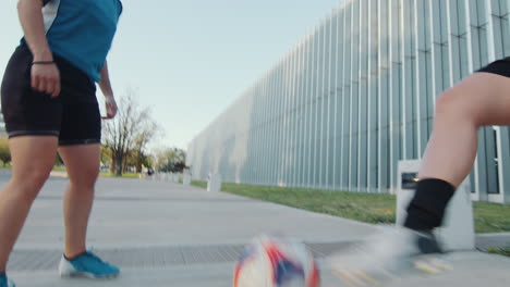 female athletes practicing soccer juggling and passing with ball on street